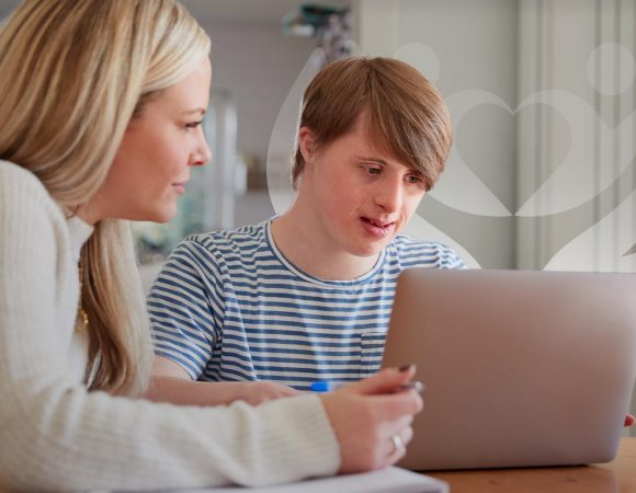 home care provider helping to use a computer to a boy